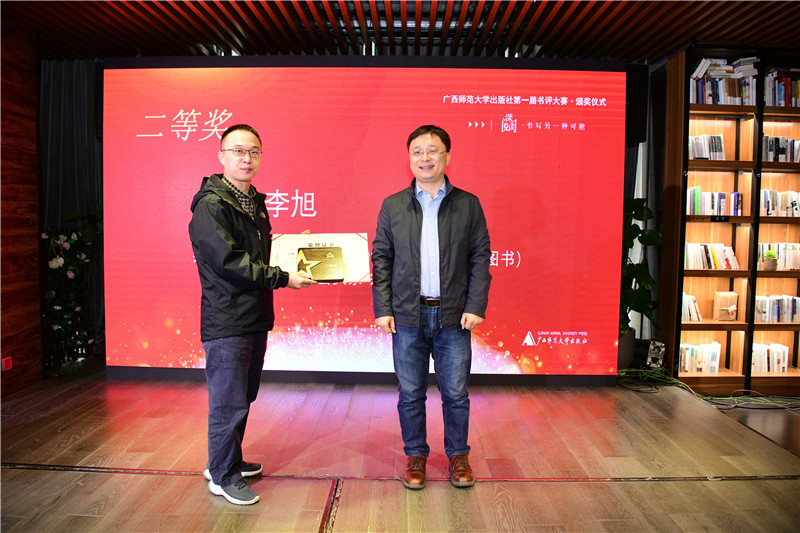 廣西師范大學(xué)出版社集團董事長(cháng)助理張俊顯（右）為二等獎獲得者王棟頒發(fā)獎牌及榮譽(yù)證書(shū)（李顯楊攝）.jpg